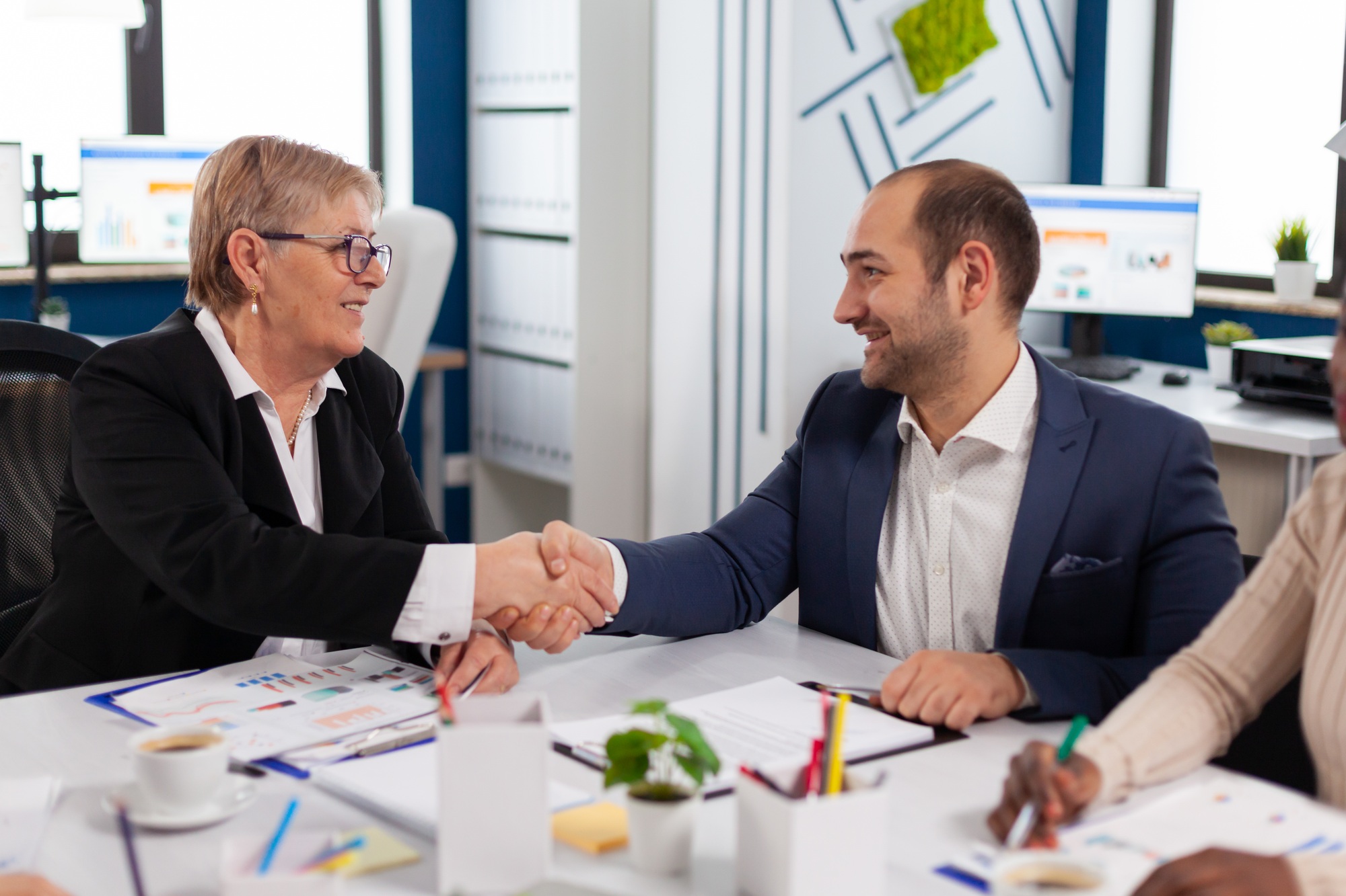 Consultant greeting international client with handshake after partnership