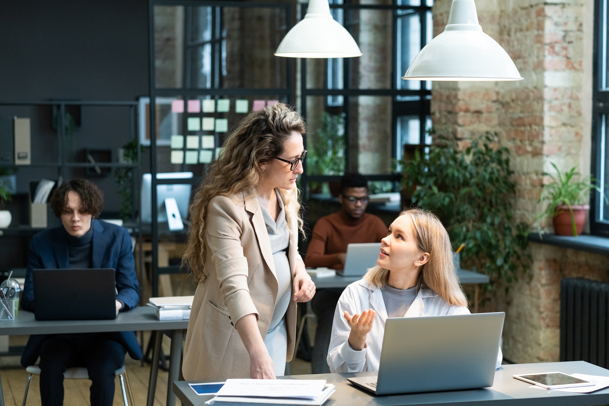 Young businesswoman explaining something to pregnant colleague